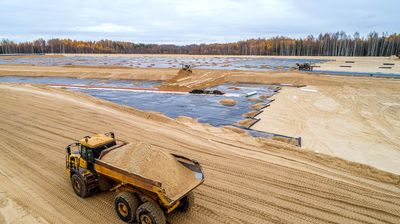 Luftaufnahme einer Deponie, auf der mehrere Baustellenfahrzeuge unterwegs sind.