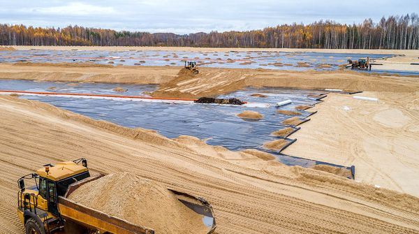 Luftaufnahme einer Deponie, auf der mehrere Baustellenfahrzeuge unterwegs sind.