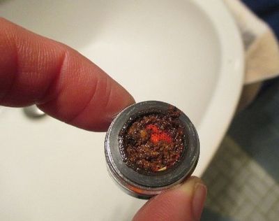 Stark verschmutzter Perlator mit sichtbaren Korrosionspartikeln und Ablagerungen, was die Wasserqualität und den Durchfluss beeinträchtigt 