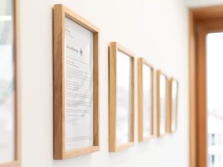 Akkreditierungsurkunde an der Wand, neben vielen weiteren Urkunden