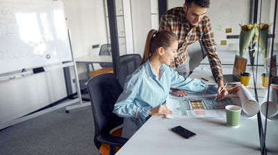 eine Bauzeichnerin und ihr Kollege besprechen einen Plan