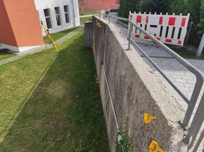 Vermessungsgeräte und gelbe Markierungen an einer Betonwand dienen der strukturellen Analyse im Außenbereich.