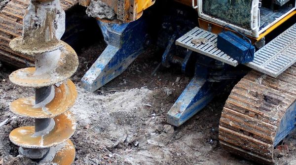 Ein Baustellenfahrzeug mit großem Bohrer steht auf einer Baustelle.