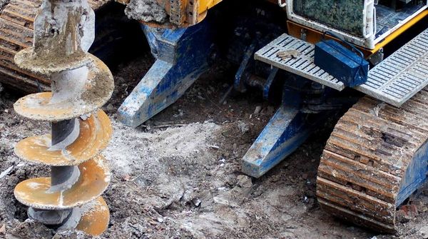 Ein Baustellenfahrzeug mit großem Bohrer steht auf einer Baustelle.