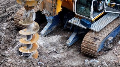 Ein Baustellenfahrzeug mit großem Bohrer steht auf einer Baustelle.