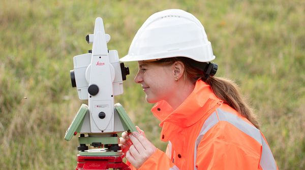 eine Auszubildende in der Vermessungstechnik schaut durch ein Tachymeter
