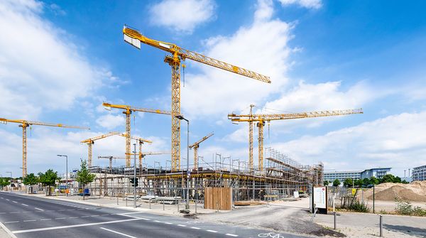 Großbaustelle mit Kränen an einer breiten Straße